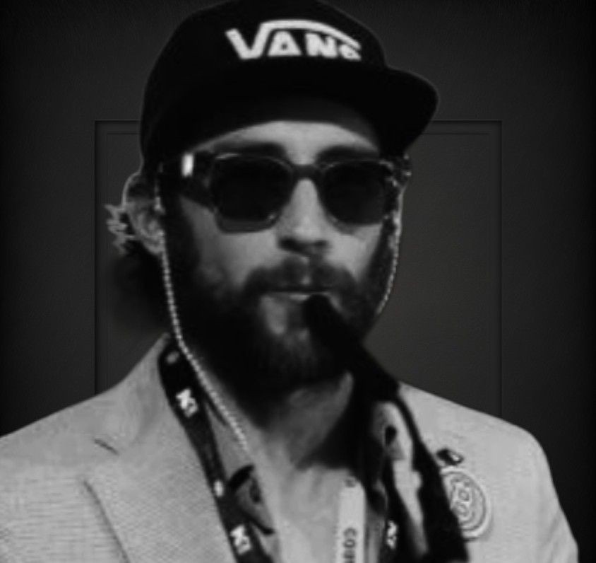 Person wearing a Vans cap, blazer, and lanyard with various badges and pins.
